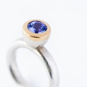 Zilver ring met diepblauwe tanzaniet in gouden zetkast.