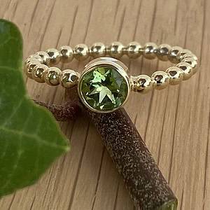 Gouden ring van pareldraad met peridoot, facet geslepen.